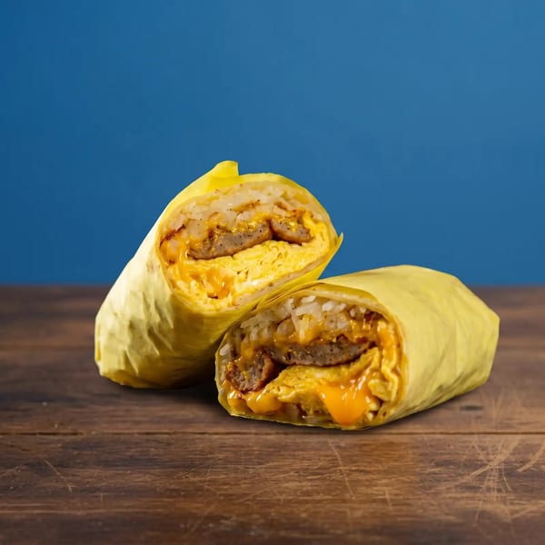 Two breakfast burritos, cut in half, revealing eggs, sausage, rice, and melted cheese on a wooden table.